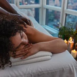 Relaxing in-home back massage in NYC with city view, candles, plants, and calming spa ambiance for stress relief.